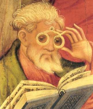 Image of a man reading. He has a beard and is using reading spectacles.